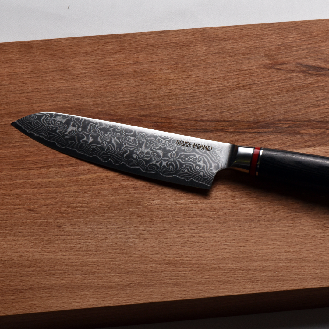 le couteau santoku rouge mermet présenté sur une planche en bois massif
