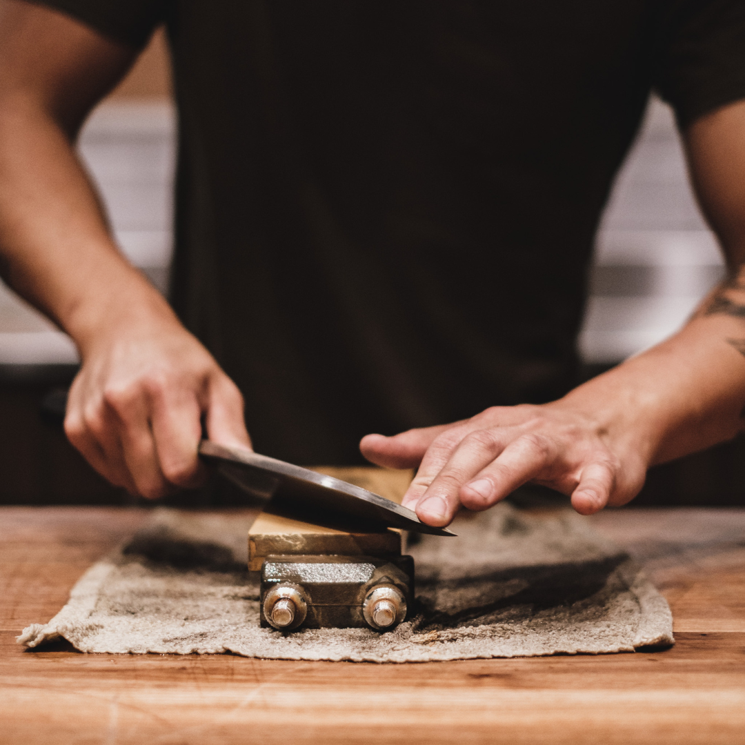 une personne affutant un couteau de cuisine sur une pierre prévue à cet effet