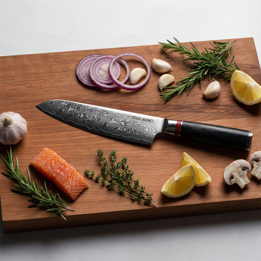 Couteau santoku Rouge Mermet en acier Damas VG10 posé sur une planche à découper