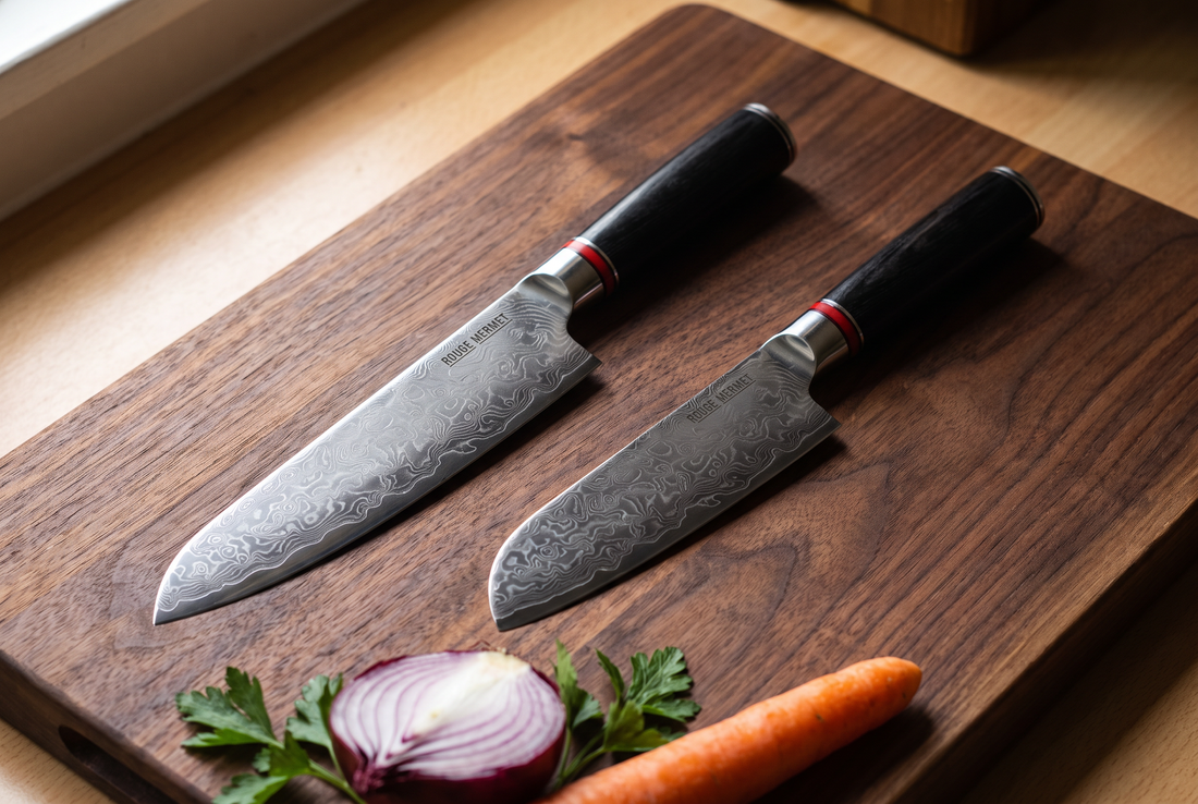Couteau de chef et santoku Rouge Mermet en acier Damas VG10 côte à côte sur une planche en noyer, avec oignon rouge, carotte et persil