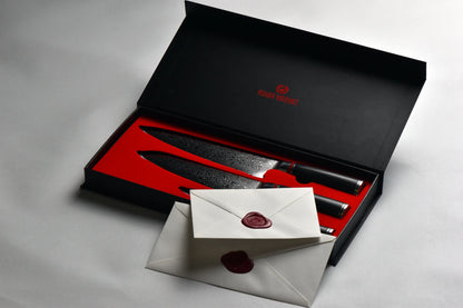 boite de 3 couteaux de cuisine. La boite est noire avec une mousse rouge. Il y à un fond blanc et les enveloppes dans lesquelles on trouve le certificat d'authenticité.